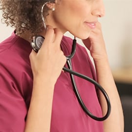 Infirmière plaçant les embouts auriculaires de son stéthoscope 3M Littmann Classic III dans ses oreilles.